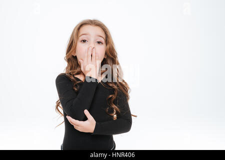 Fatigué curly petite fille debout et de bâiller sur fond blanc Banque D'Images