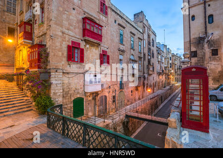 La Valette, Malte - Rouge téléphone vintage britannique fort et passerelle et d'un balcon rouge traditionnel dans l'ancienne ville de La Valette tôt le matin Banque D'Images