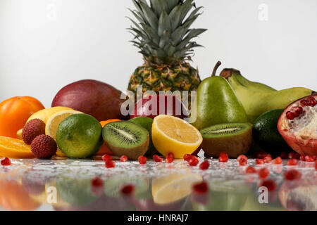 Fruits tropicaux juteux avec des gouttes d'eau sur une surface blanche. Grande réflexion de fruits Banque D'Images