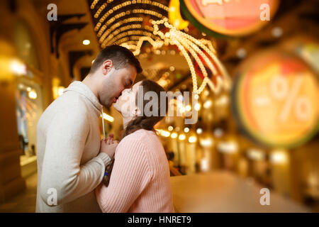 Kissing couple shopping au milieu de guirlandes Banque D'Images