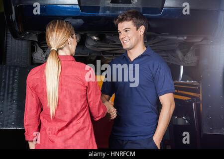 Smiling mechanic shaking hand avec le client Banque D'Images