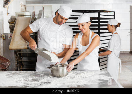 Hommes et femmes travaillant ensemble dans Baker's Bakery Banque D'Images