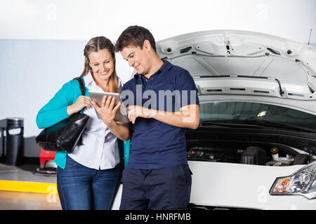 Client à l'aide de tablette numérique avec le mécanicien Banque D'Images