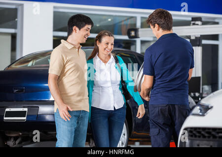 Couple discussing over alliage avec mechanic Banque D'Images