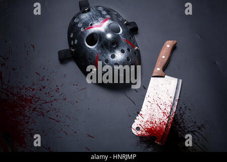 Outils de meurtrier en série isolé sur fond noir. Couperet à viande sanglante et masque de hockey Banque D'Images