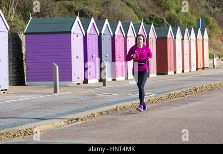 Bournemouth, Dorset, UK. 16 Février, 2017. Météo France : belle journée ensoleillée à la plage de Bournemouth, en tant que visiteurs, chef de la station pour profiter du soleil pour les petites vacances. Femme bénéficie de l'ensoleillement en marche le long de la promenade du cours des cabines colorées Crédit : Carolyn Jenkins/Alamy Live News Banque D'Images