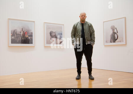 Wolfsburg, Allemagne. 16 Février, 2017. L'artiste sud-africain Pieter Hugo pose devant des photos du Ghana à l'exposition de photos "entre le marteau et l'enclume" au Kunstmuseum (Musée d'art') à Wolfsburg, Allemagne, 16 février 2017. C'est la première exposition solo institutionnel du photographe en Allemagne. Hugo se concentre sur les moyens des gens différents vivent ensemble dans les dictatures. Photo : Julian Stratenschulte/dpa/Alamy Live News Banque D'Images