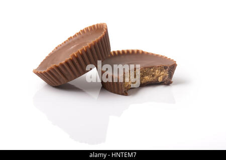 Deux tasses de beurre d'arachide de chocolat, une avec une morsure pris hors de lui, le blanc avec la réflexion et l'ombre. Banque D'Images