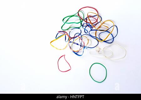 Un assortiment aléatoire de couleur primaire de bandes de caoutchouc, autrement connu comme des élastiques, rouge, bleu, vert, sur un fond blanc, zone de texte à gauche Banque D'Images