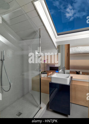 Vue intérieure d'une salle de bains moderne dans la mansarde avec cabine de douche en verre et le plan de lavabo Banque D'Images