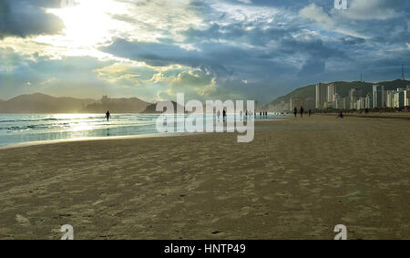 Plage au coucher du soleil avec des gens qui marchent dans le sable Banque D'Images