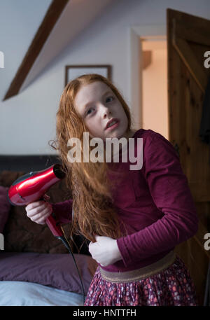 Une petite fille sécher les cheveux avec un sèche-cheveux Banque D'Images