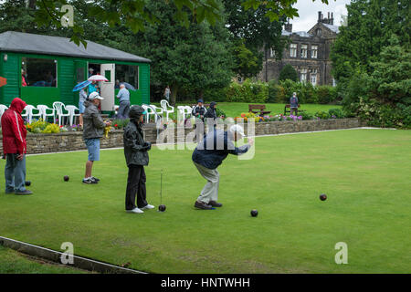 Les concurrents et les spectateurs (sous la pluie) à un match de Bowling Green de la couronne sur le village bowling green - Burley Dans Wharfedale, West Yorkshire, Angleterre. Banque D'Images