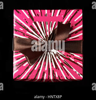 Un présent fort colorés avec ruban brun isolé sur fond noir Vue de dessus Banque D'Images