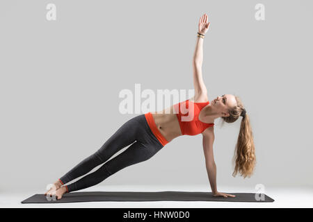 Young attractive woman standing in Side planche, studio gris Banque D'Images