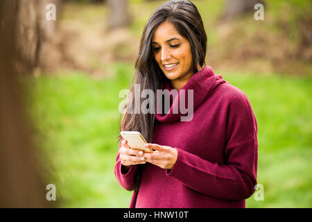 Smiling woman texting on cell phone Banque D'Images