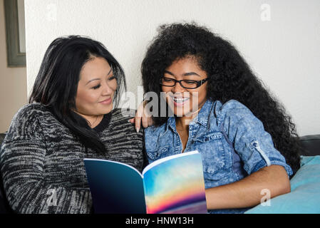 Smiling mother and daughter reading book Banque D'Images