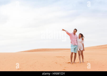 Jeune homme Woman in Desert Beautiful Couple Asian Girl et Guy pointer du doigt embrasser Sand Dune Banque D'Images