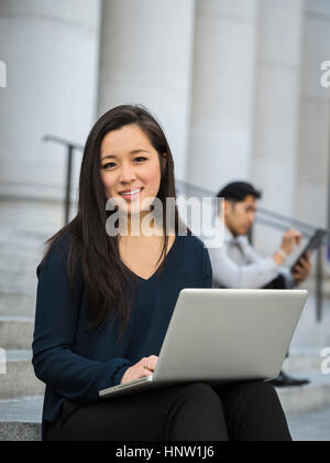 Chinese businesswoman sitting on staircase using laptop Banque D'Images