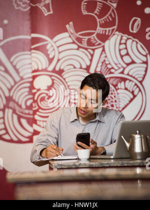 Chinese businessman talking on cell phone in restaurant Banque D'Images