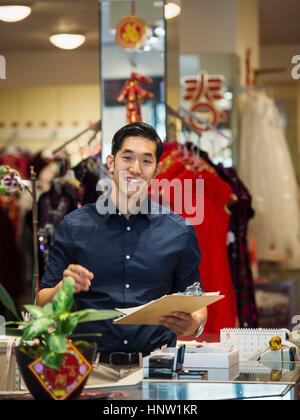 Chinese man writing on clipboard in store Banque D'Images