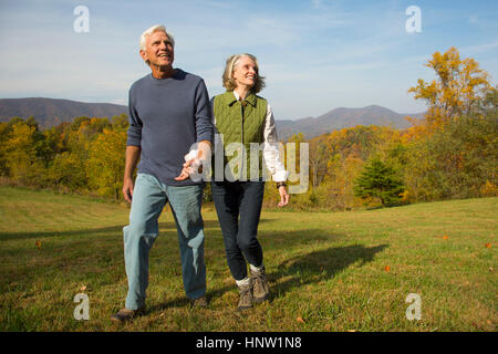 Caucasian couple walking in field Banque D'Images