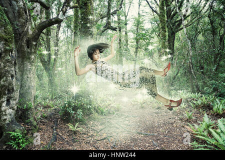 Mixed Race girl floating in forest Banque D'Images