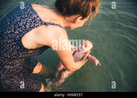 Caucasian mother holding baby daughter in ocean Banque D'Images