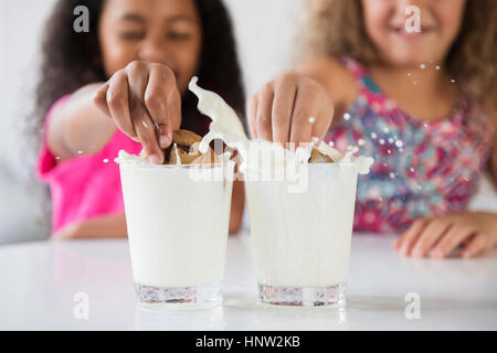 Les filles des éclaboussures les cookies dans verres de lait Banque D'Images