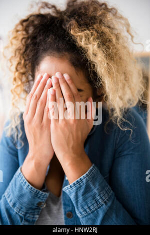 Mixed Race woman covering face with hands Banque D'Images