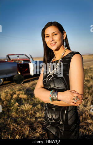 Portrait of smiling woman standing in grass près de voiture Banque D'Images