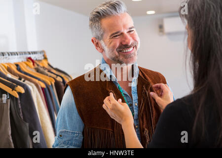 Femme Homme aidant avec gilet fringe en magasin Banque D'Images