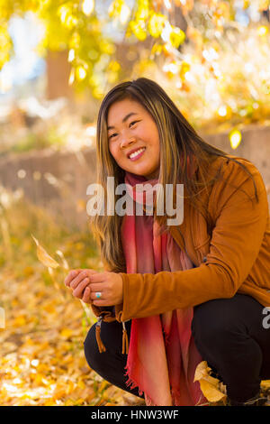 Smiling Asian woman holding leaf en automne Banque D'Images