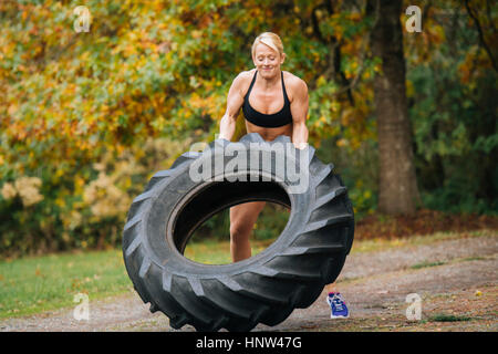 Caucasian woman soulever de lourdes tire in park Banque D'Images