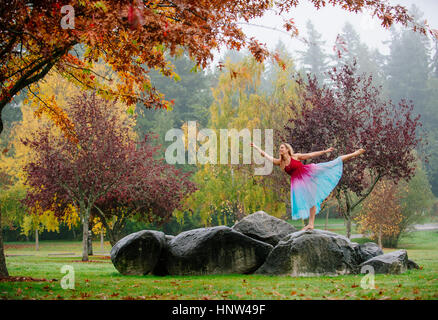Caucasian ballerina dancing on rocks in park Banque D'Images