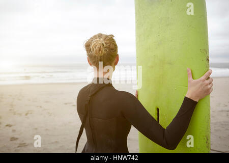 Femme surfer holding surfboard à partir de Rockaway Beach, New York, USA Banque D'Images