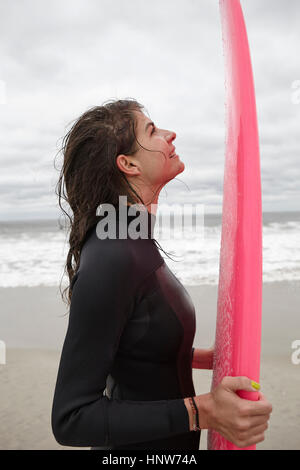 Portrait of young female surfer holding surfboard rose sur Rockaway Beach, New York, USA Banque D'Images