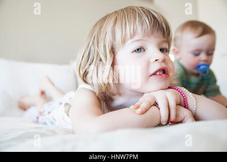 Portrait of Girl et baby brother lying on bed Banque D'Images