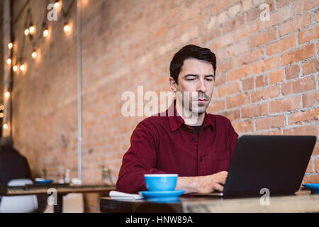 Man working on laptop at cafe Banque D'Images