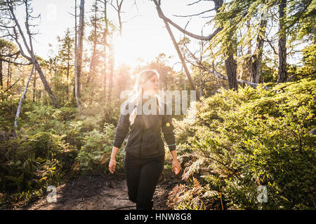 Female hiker la randonnée à travers la forêt tropicale ensoleillée, parc national Pacific Rim, l'île de Vancouver, Colombie-Britannique, Canada Banque D'Images