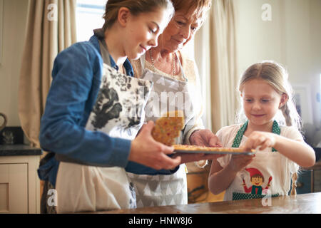 Senior Woman picking et petites-filles des cookies d'arbre de Noël Banque D'Images