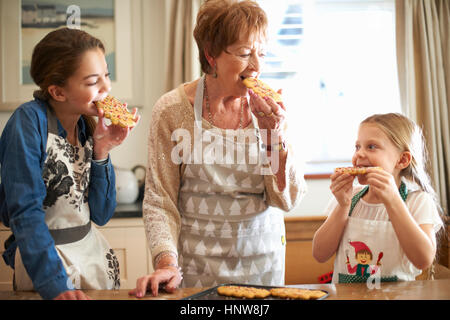 Senior woman et petites-filles de manger des cookies d'arbre de Noël Banque D'Images