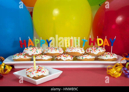 Gâteau donut miniature sur plaque blanche avec joyeux anniversaire bougies un donut sur plaque carrée unique avec une seule bougie bleue. Premier anniversaire parfait Banque D'Images