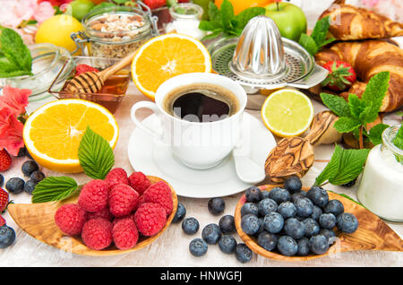Le petit-déjeuner avec café, croissants, céréales, fruits frais, fruits rouges, orange, pomme, lait. Concept d'aliments sains Banque D'Images