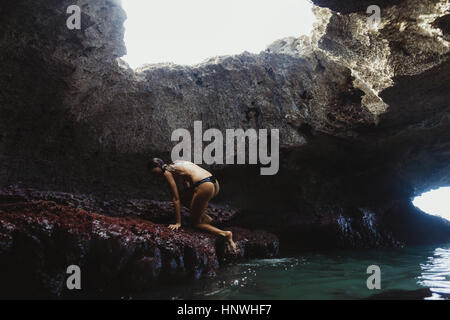 Jeune femme escalade sur des rochers, grottes Mermaid, Oahu, Hawaii, USA Banque D'Images