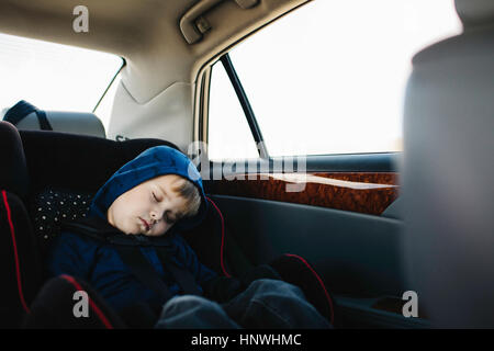 Jeune garçon endormi in back seat of car Banque D'Images