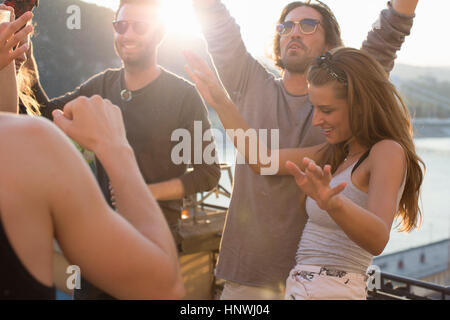 Adult friends dancing au coucher du soleil terrasse sur le toit, Budapest, Hongrie Banque D'Images