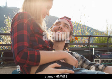 Jeune femme assise sur les genoux d'petit ami sur la terrasse du toit Banque D'Images