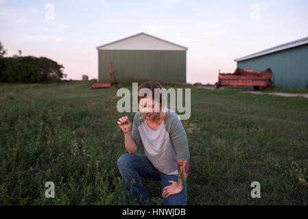 Woman on farm, accroupi, odeur de plante Banque D'Images