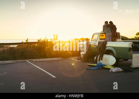 Vue arrière du couple en arrière de camionnette regardant le coucher du soleil à Newport Beach, Californie, USA Banque D'Images